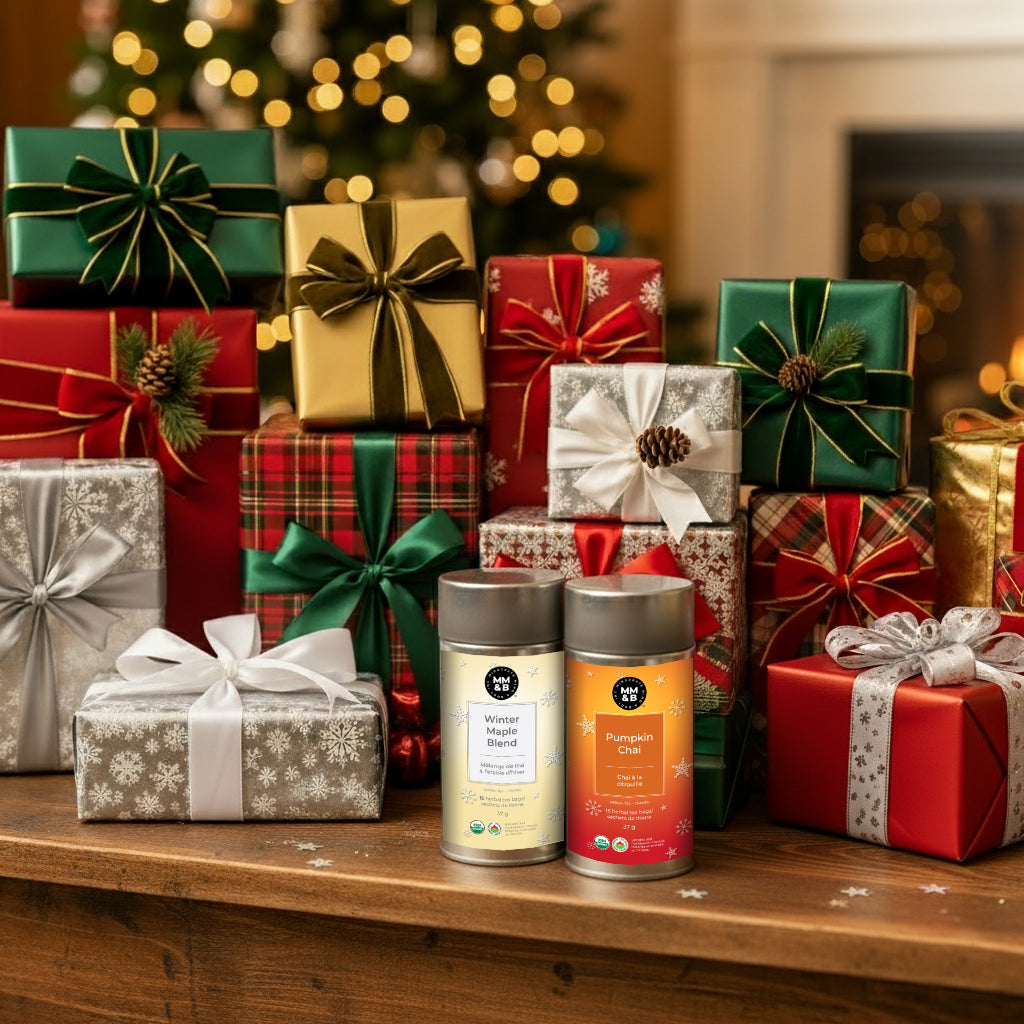 The Perfect Sip Bundle holiday gift set featuring two tea canisters: Organic Pumpkin Chai and Organic Winter Maple Blend, sitting in front of wrapped Christmas presents.
